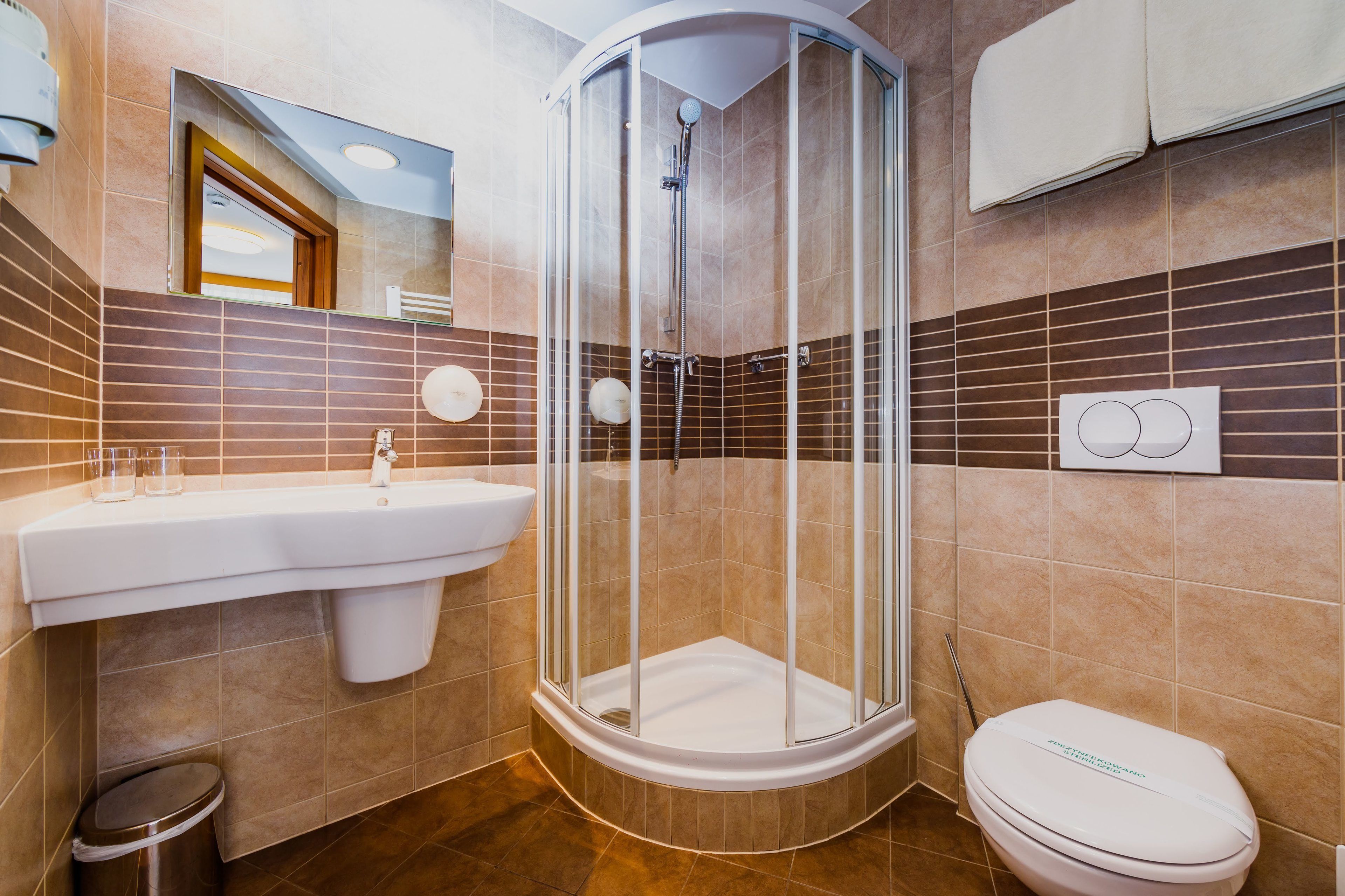 A bathroom with a glass-enclosed shower, a sink, and a toilet.