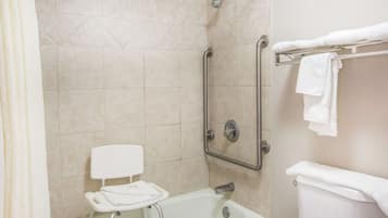 Un baño con ducha, inodoro y barra de apoyo.