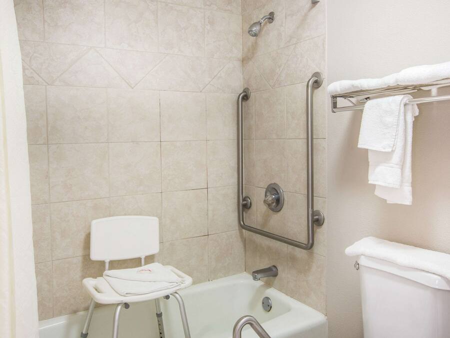 Un baño con ducha, inodoro y barra de apoyo.