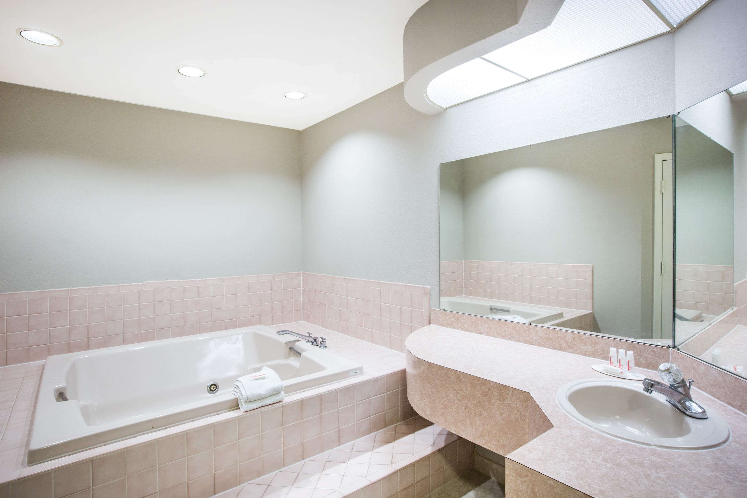 A modern bathroom with a large bathtub, a sink, and a mirror.
