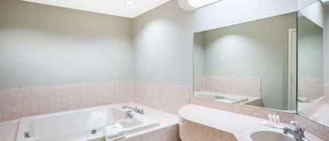 A modern bathroom with a large bathtub, a sink, and a mirror.
