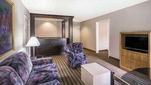 A hotel room with a large bed, a sofa, a TV, and a mirror.