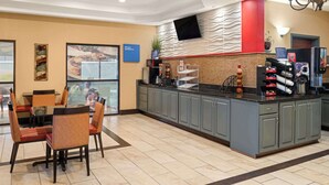 A hotel lobby with a dining area, a kitchen counter, and a TV mounted on the wall. - Ramada by Wyndham Locust Grove (Locust Grove)