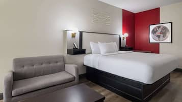 Una habitación de hotel con cama, sofá, mesita de noche y un globo terráqueo en la pared.