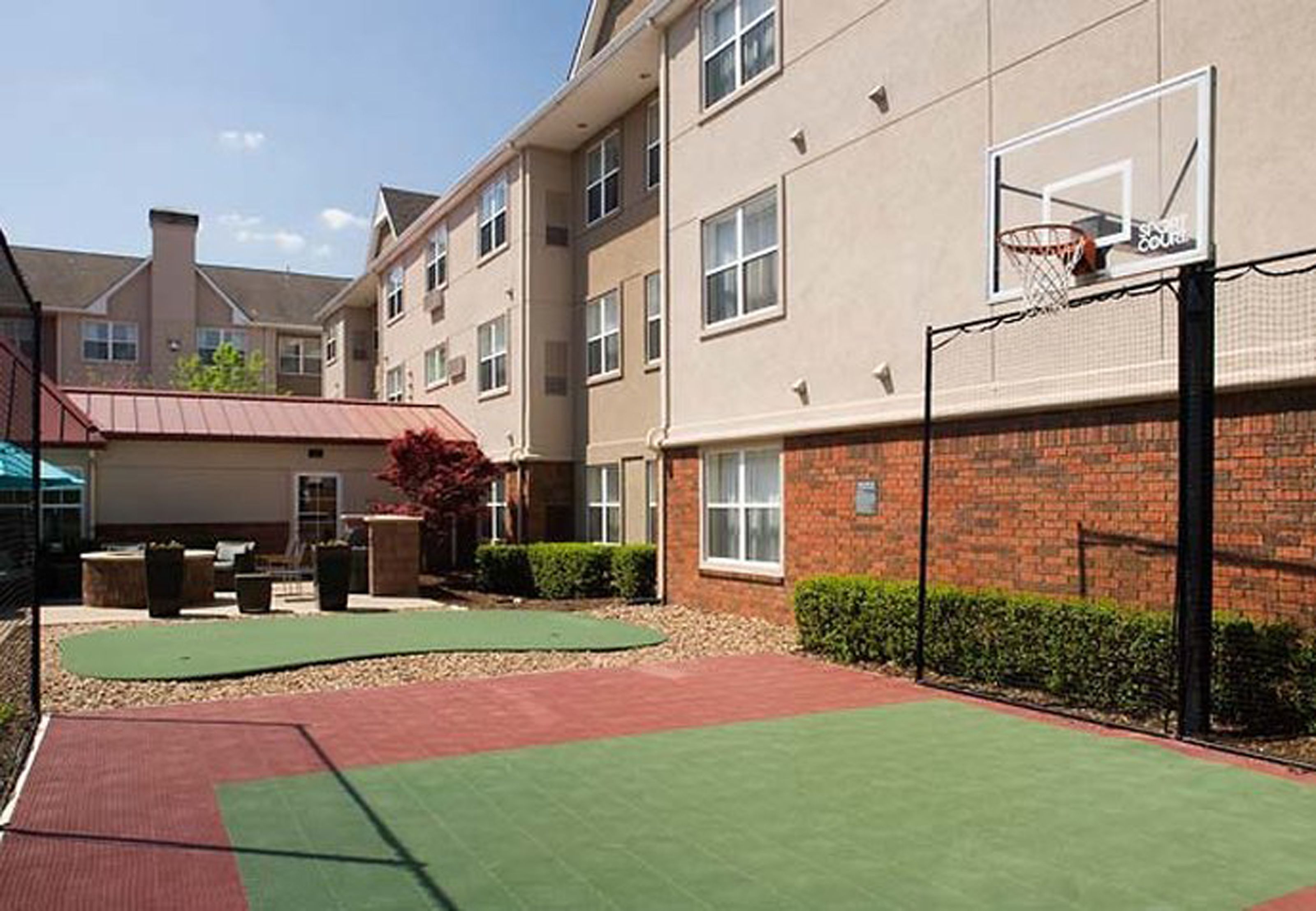 A basketball court adjacent to a building with a basketball hoop.