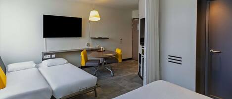 Una habitación de hotel con cama, escritorio, silla, televisión y puerta.