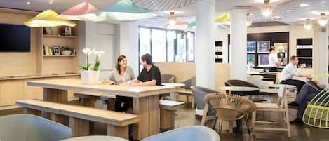 A modern cafe with wooden tables, comfortable seating, and unique ceiling light fixtures.