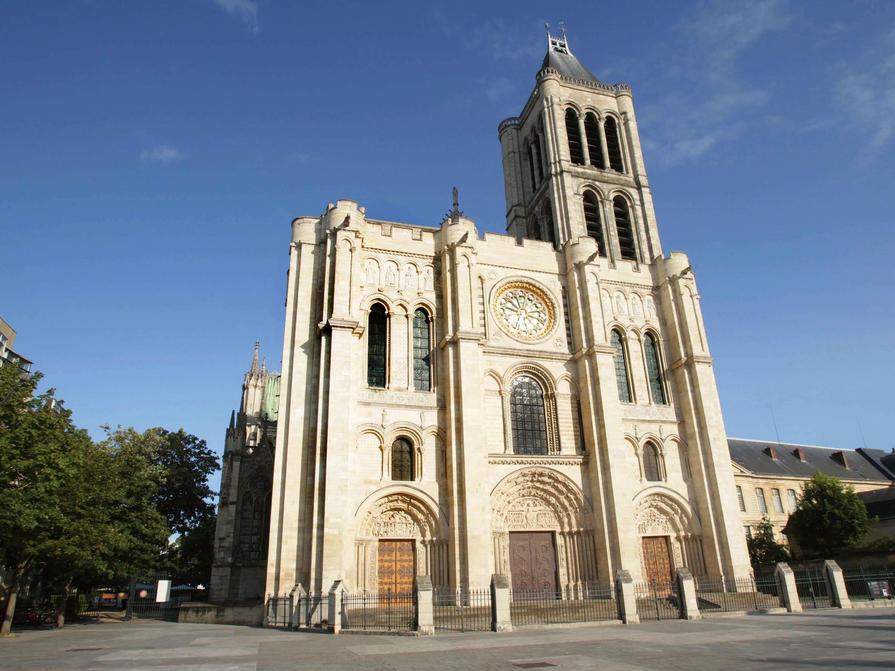 A large cathedral with a prominent clock tower, arched windows, and detailed stonework.