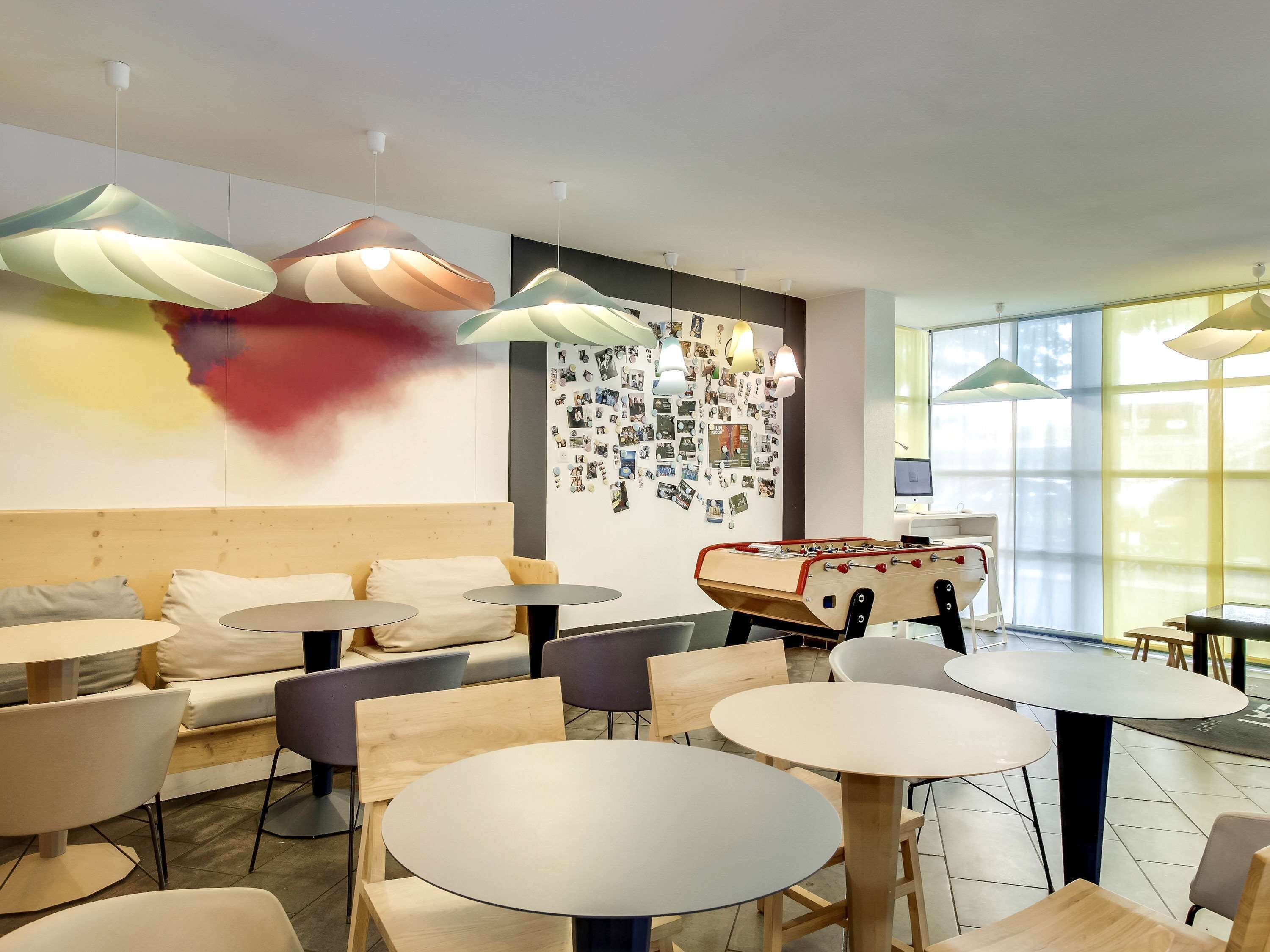 Un espace de détente moderne avec des tables rondes, des sièges confortables et une table de baby-foot.