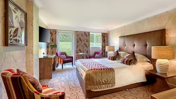 A hotel room with a large bed, a TV, a desk, and a chair.