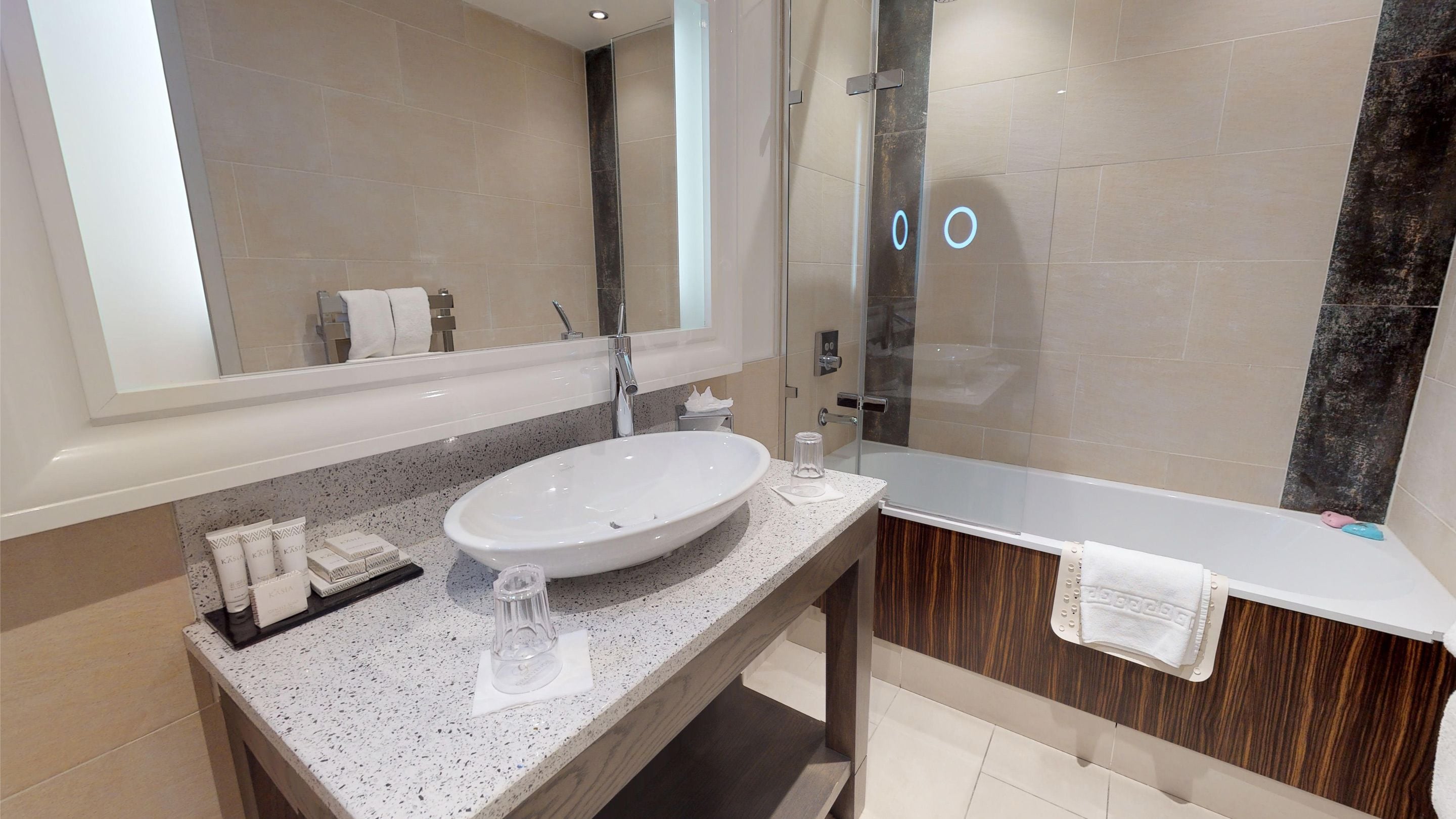 A modern bathroom with a large oval sink, a glass shower enclosure, and a wooden vanity.