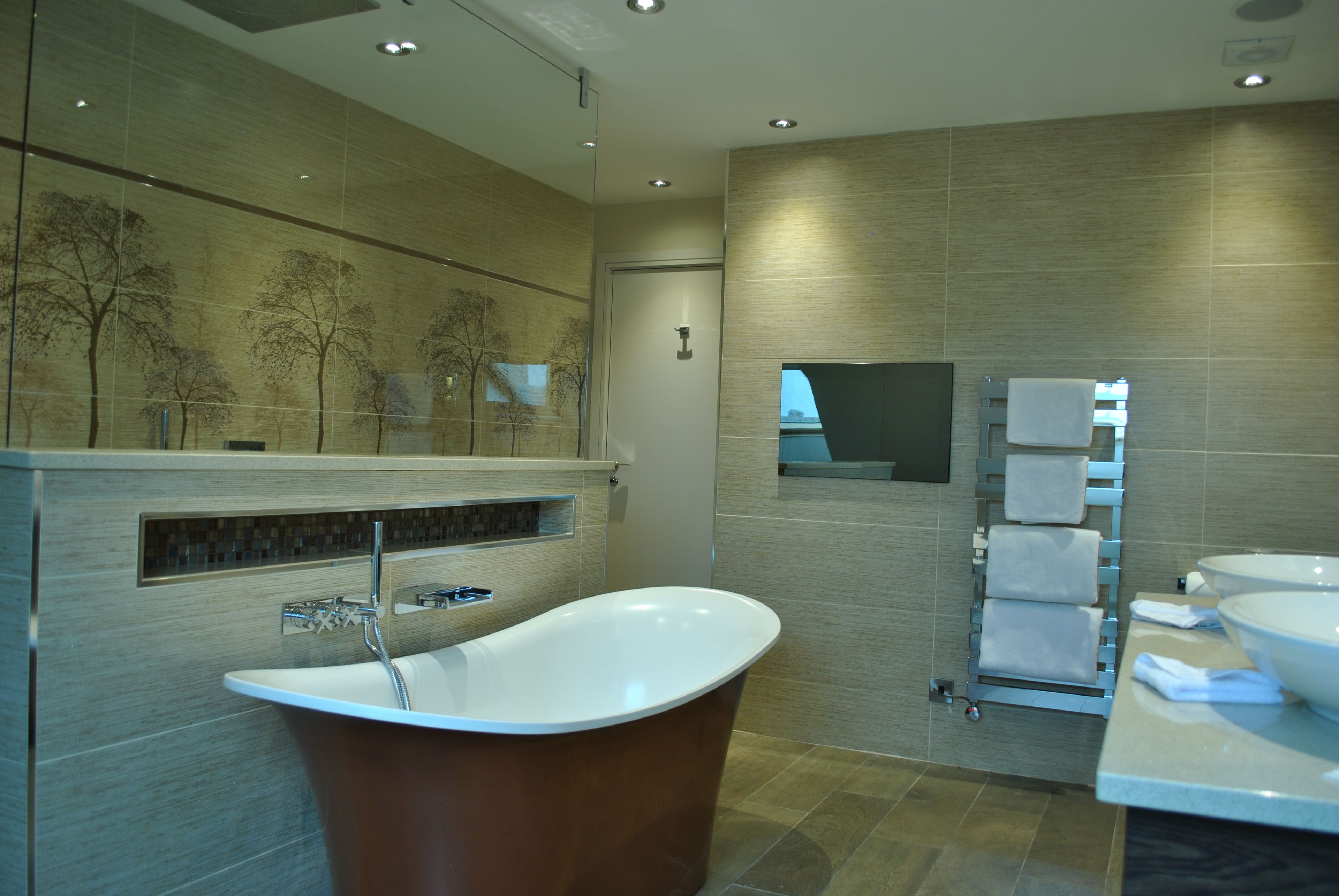 A modern bathroom with a freestanding bathtub, a large mirror, and a towel rack.