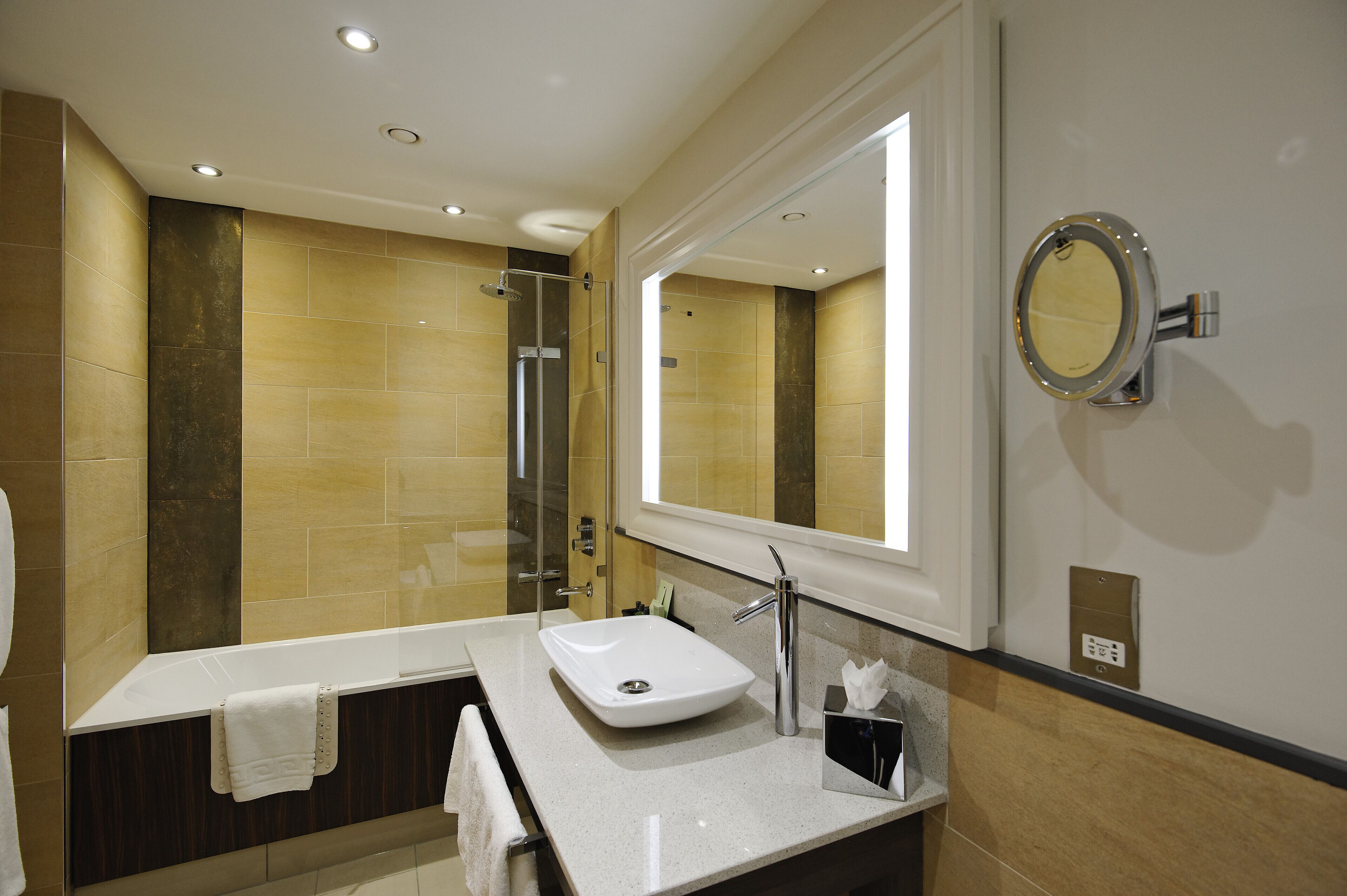 Une salle de bain moderne avec un grand miroir, un lavabo et un espace douche.