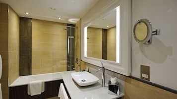 A modern bathroom with a large mirror, a sink, and a shower area.