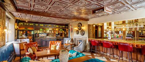 A bar area with a wooden ceiling, bar stools, and a seating area with a sofa and chairs.