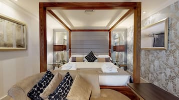 A modern hotel room with a large bed, a sofa, a small table, and a mirror.