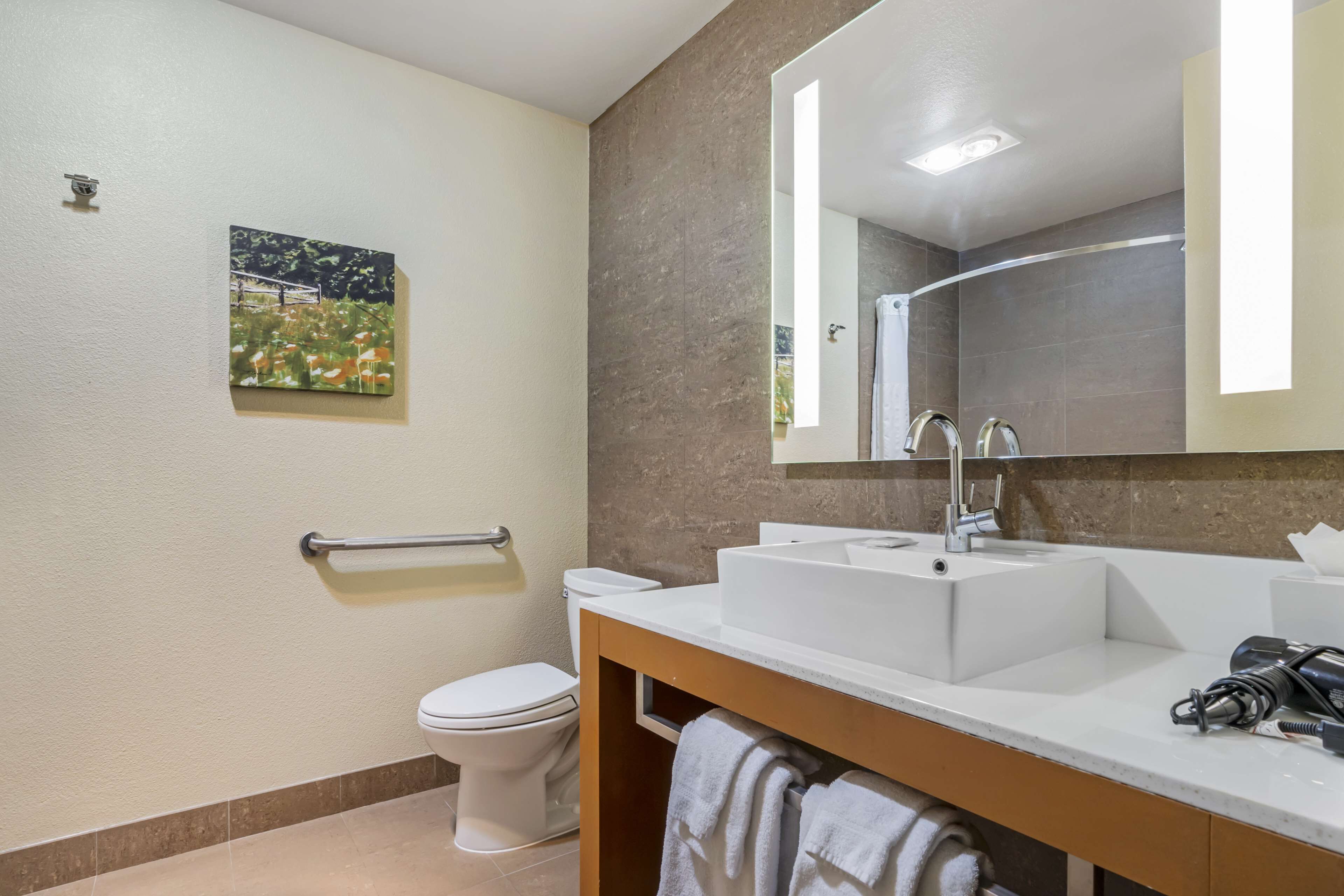 Ein modernes Badezimmer mit einem weißen Waschbecken, einem großen Spiegel und einer Toilette.