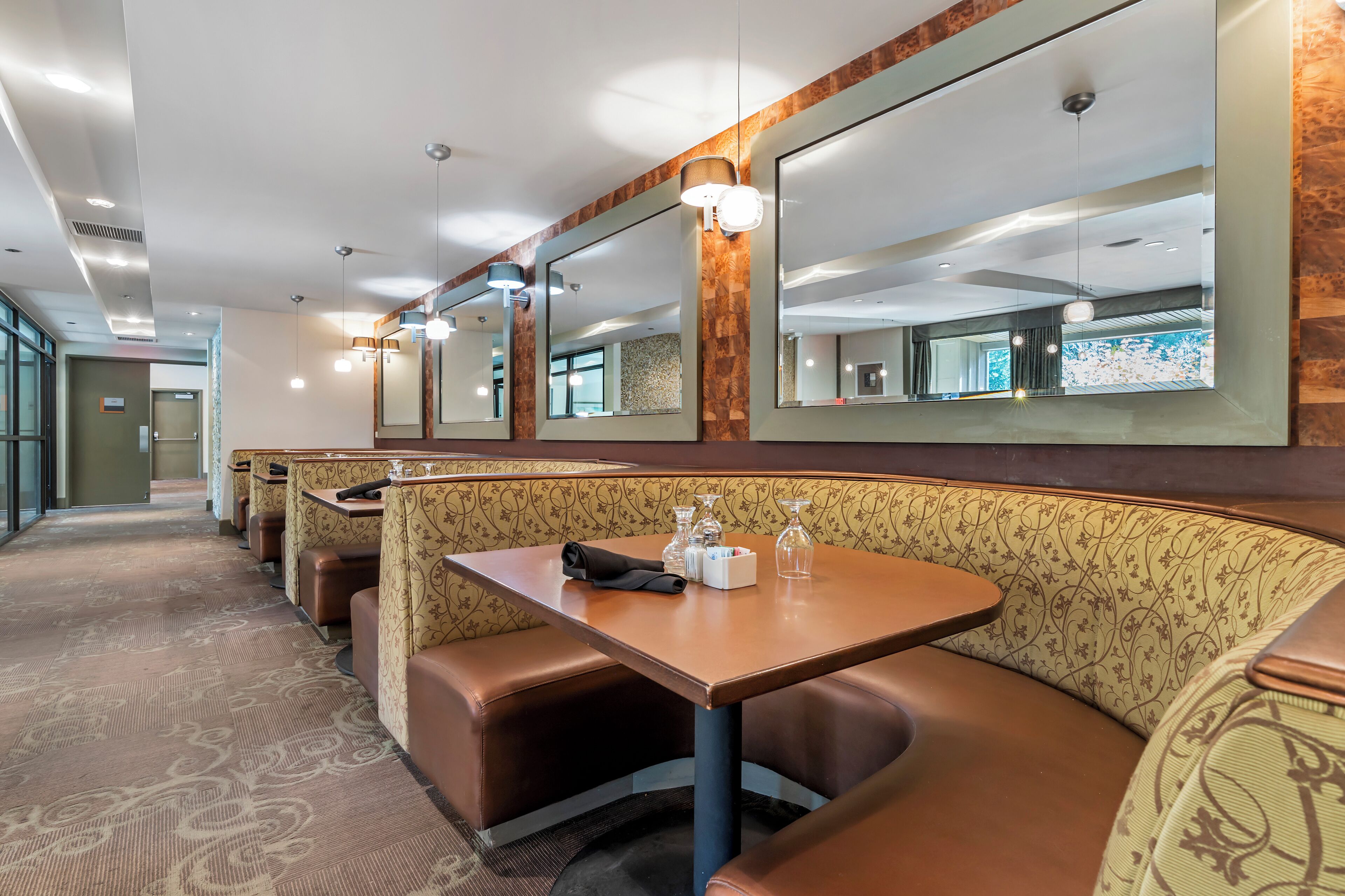 A restaurant with booth seating, a long counter, and a large mirror on the wall.