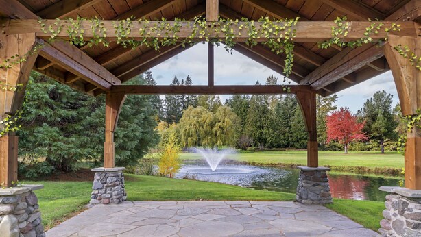 A gazebo with stone pillars and a stone pathway leading to a pond with a fountain. - Mt Hood Oregon Resort, BW Premier Collection (Welches)