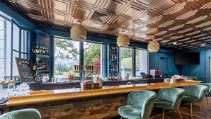 A bar area with a wooden counter, green bar stools, and shelves stocked with bottles. - Mt Hood Oregon Resort, BW Premier Collection (Welches)