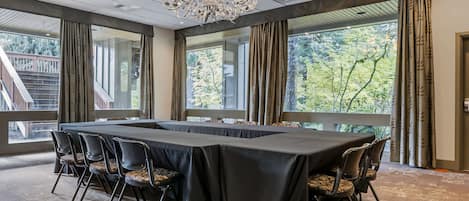 Une salle de conférence avec une longue table, des chaises et un lustre.