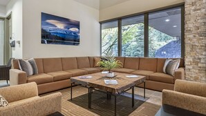 A modern living room with a sectional sofa, a coffee table, and a large window with a view of trees. - Mt Hood Oregon Resort, BW Premier Collection (Welches)