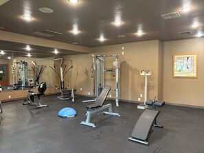 Un gimnasio con equipo de ejercicio, un espejo y un cuadro en la pared.