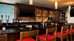 Un área de bar con sillas de madera, una encimera negra y varios botellas y vasos.