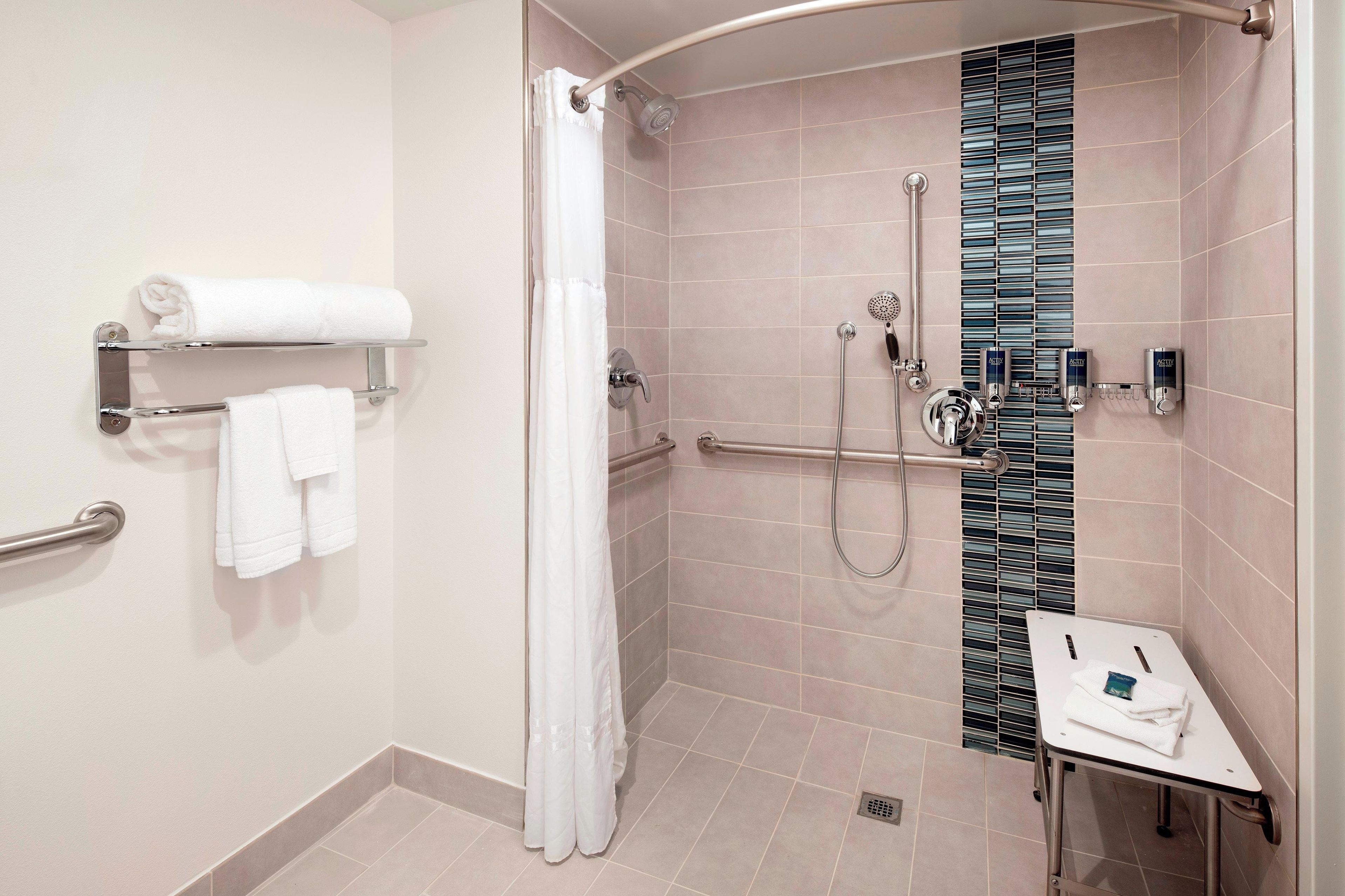 Un baño moderno con ducha, un perchero y una mesita con una toalla.