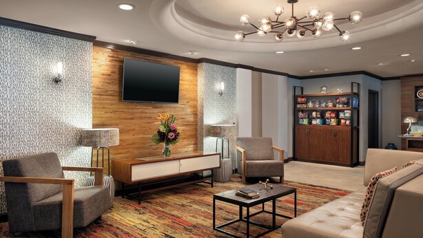 Una sala de estar moderna con un sofá, sillones, una mesa de centro y un televisor montado en la pared.