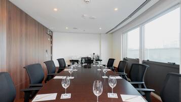 A conference room with a long table, multiple chairs, and wine glasses.
