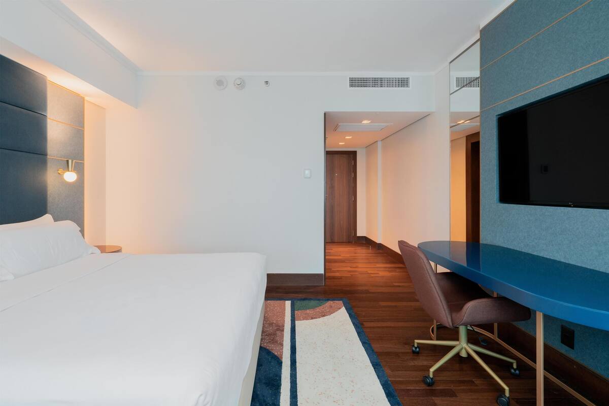 Een hotelkamer met een bed, een bureau, een stoel en een televisie.