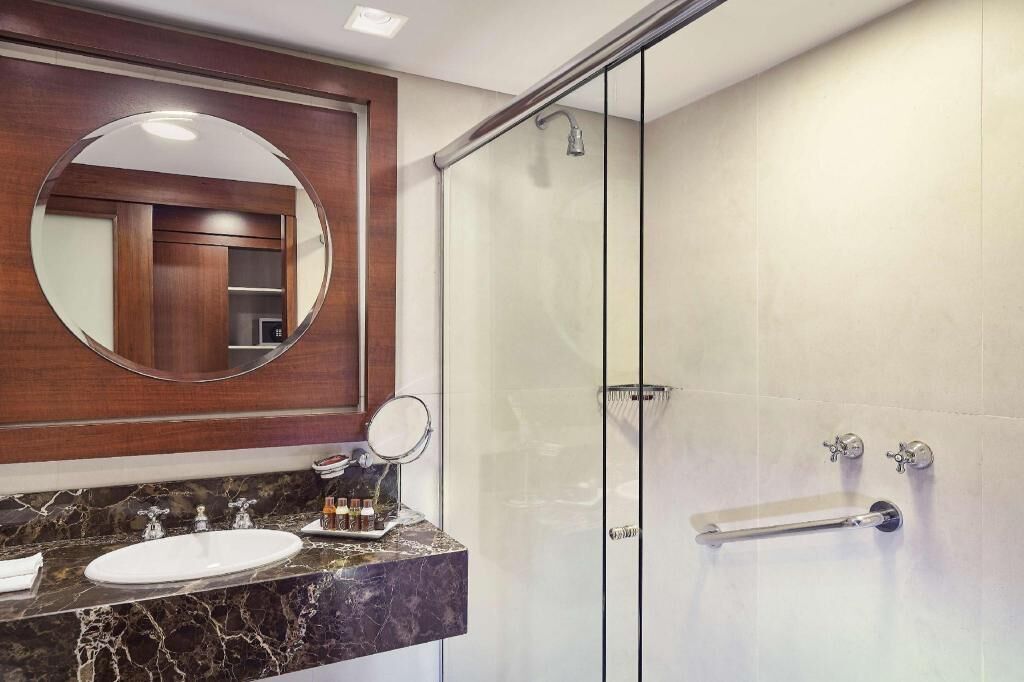 Une salle de bain moderne avec une douche à l’italienne en verre, un lavabo en marbre et un grand miroir.