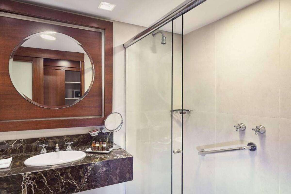 Een moderne badkamer met een glazen douchecabine, een marmeren wastafel en een grote spiegel.