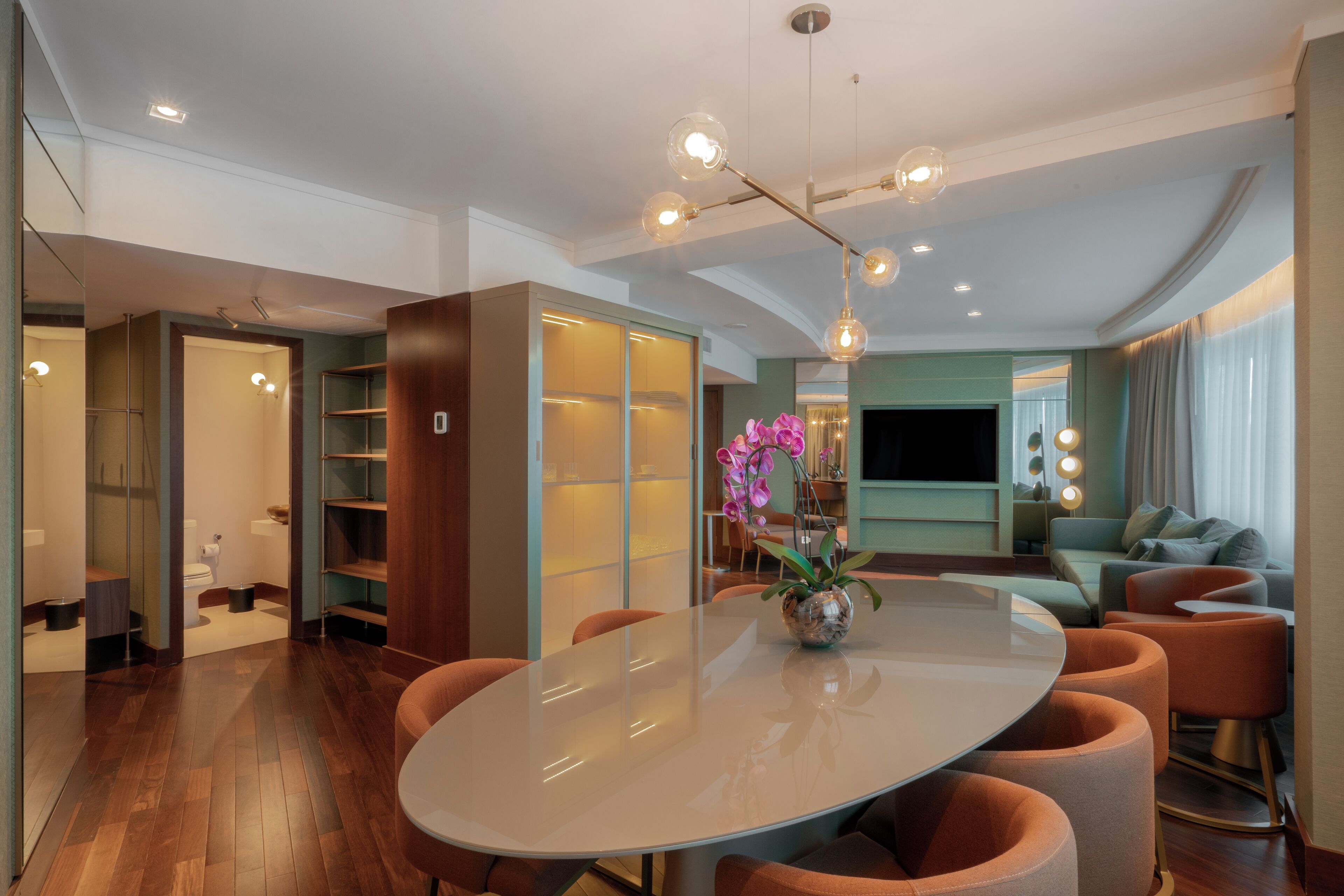 Un espace repas moderne avec une table ronde, des chaises orange et un vase de fleurs.