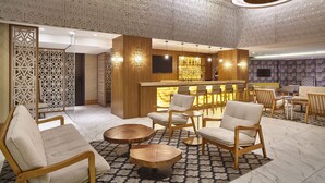 Un vestíbulo moderno con mobiliario de madera, una zona de bar y paneles decorativos en el techo.