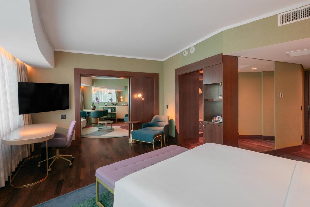 Een hotelkamer met een groot bed, een bureau met stoel, een televisie en een kitchenette.