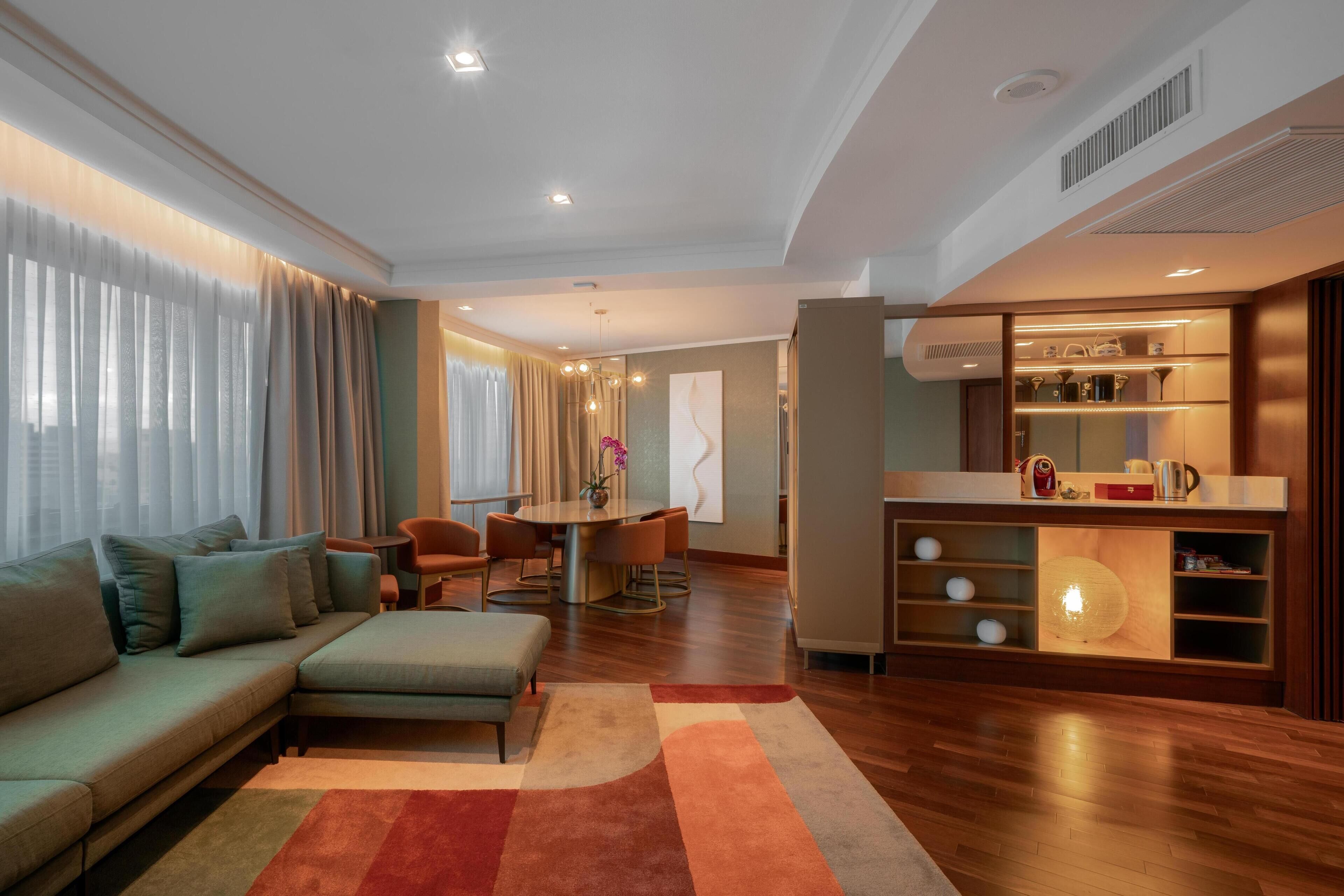 Una sala moderna con sofá, reposapiés y un comedor con mesa y sillas.