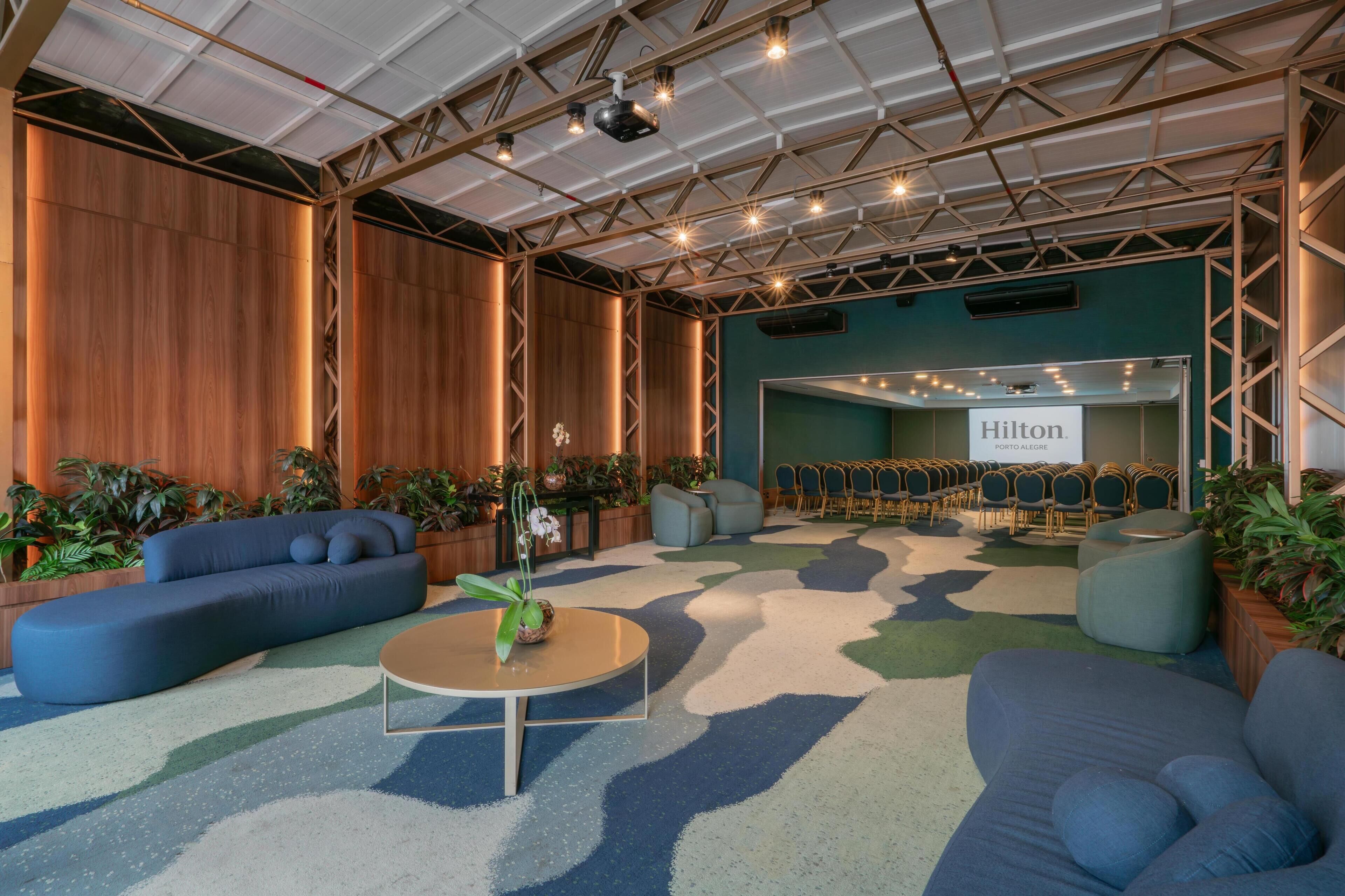 A spacious lobby with a blue sofa, a coffee table, and a seating area with chairs.