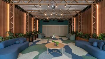 A room with a wooden ceiling, a round table, two sofas, and potted plants.