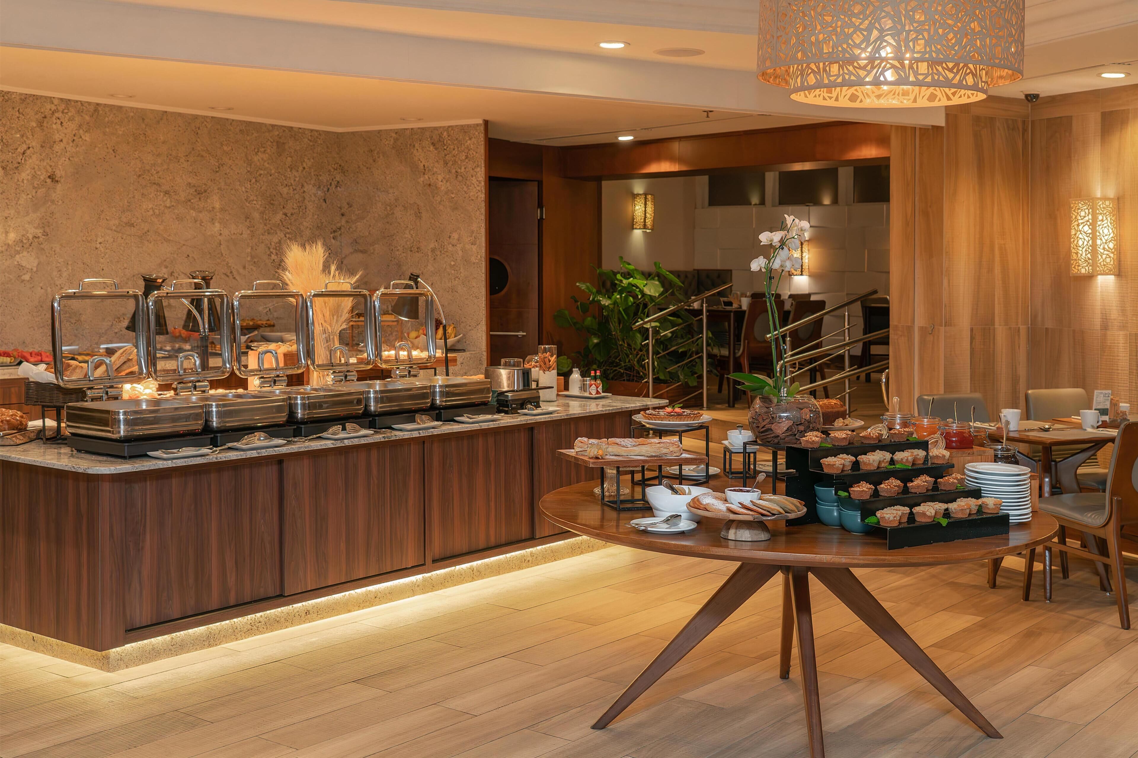 A buffet setup with various food items and a seating area with tables and chairs.