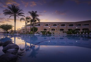 A hotel with a pool, palm trees, and a sunset. - Sol Sun Beach Apartamentos (Adeje)