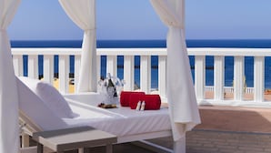 A white canopy bed with a view of the ocean, a table with a bottle and glasses, and a red towel. - Sol Sun Beach Apartamentos (Adeje)