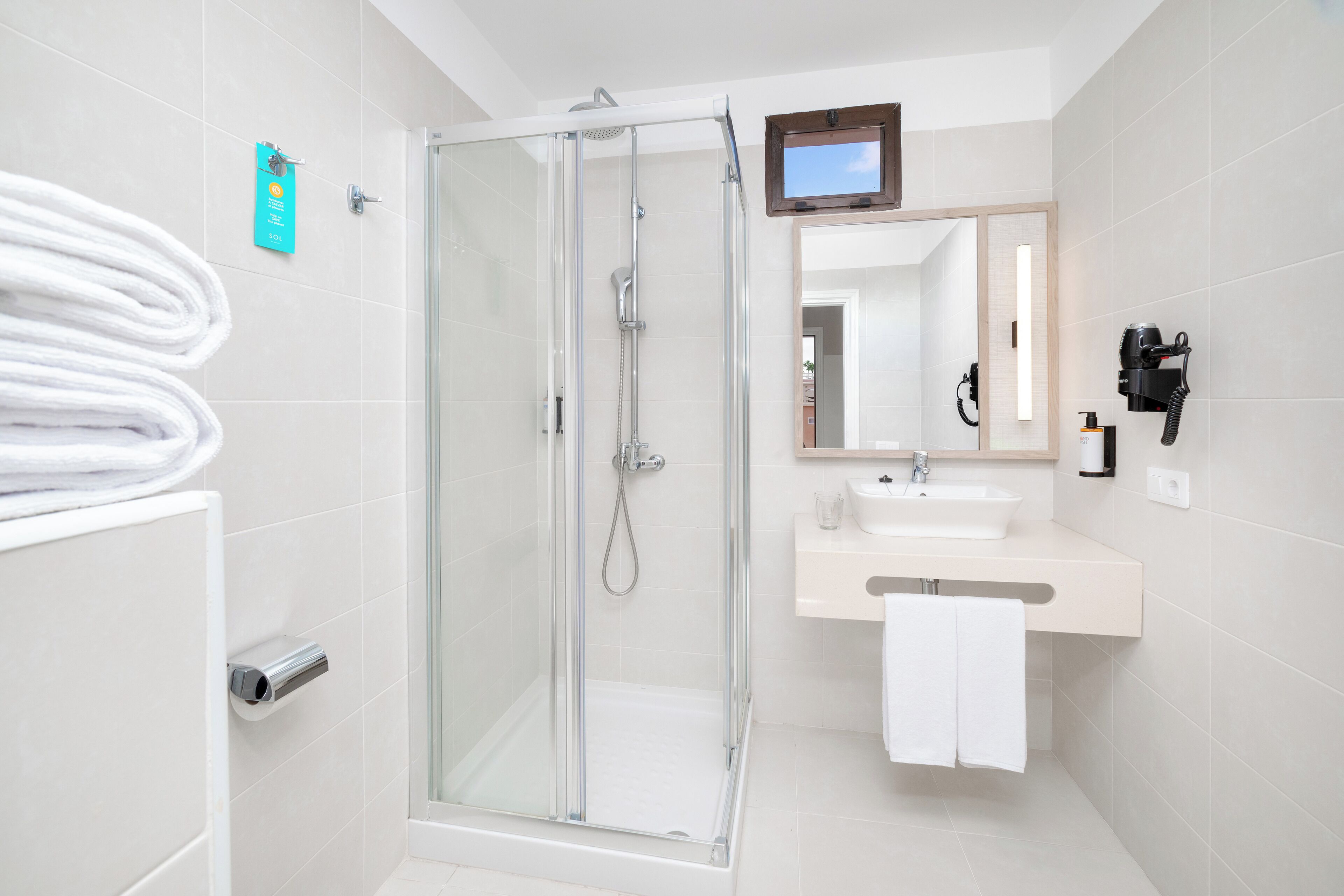 Un bany modern amb dutxa de vidre, un lavabo i un mirall.