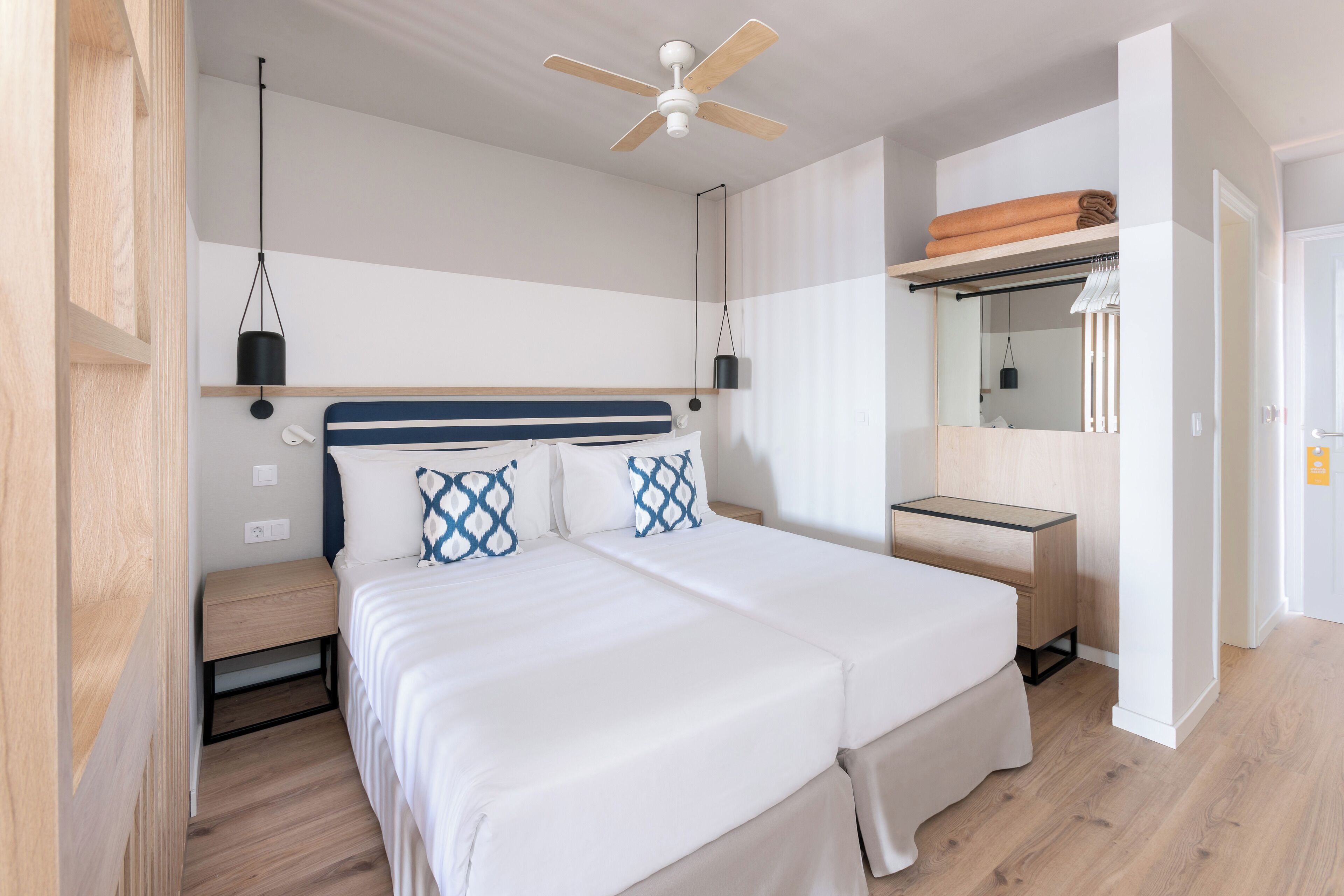 A modern bedroom with a large bed, bedside tables, a ceiling fan, and a wardrobe.