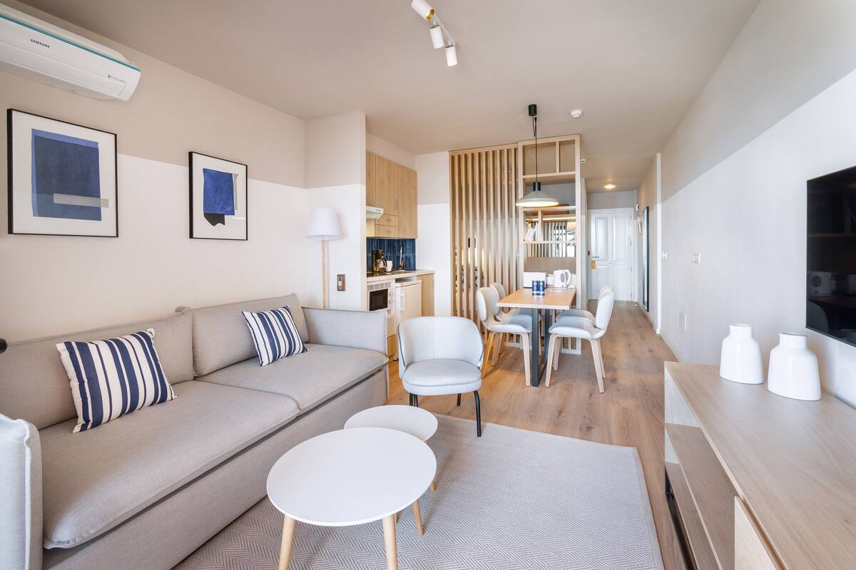 Uma sala de estar moderna com sofá, cadeiras, mesa de jantar e televisão.