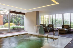 Una piscina cubierta, una piscina al aire libre, tumbonas