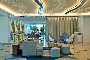 A modern lobby with a reception desk, seating area, and decorative ceiling elements.