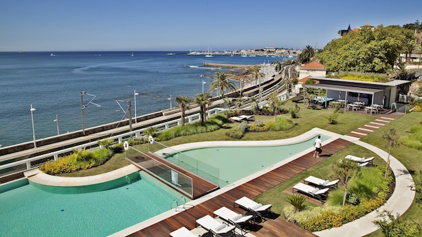 Un complexe hôtelier doté d’une piscine, de chaises longues et offrant une vue sur la mer.