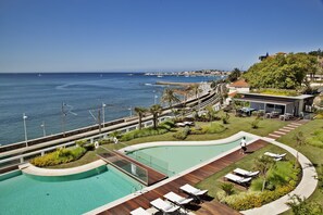 Un resort con piscina, sillones de descanso y vistas al mar.